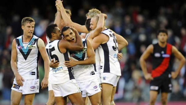 Port Adelaide players celebrate with 100-gamer Danyle Pearce after their thrilling win over the Bombers yesterday.