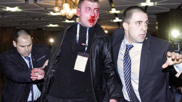 Unsuccessful ... Bulgarian security officers escort the bloodied  25 year old man after his attack on Ahmed Dogan.