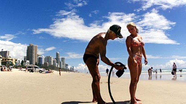 Al Baldwin sprays a beachgoer with sunscreen at Surfers Paradise, where he held court for 30 years.