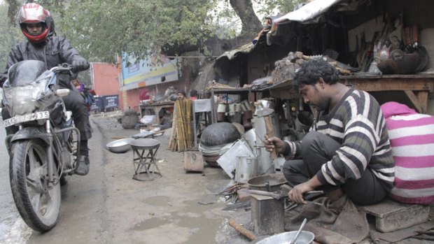 Vikram, a Rajasthani blacksmith and member of the nomadic Gadia Lohar tribe, works outside his home, which is built on the side of a busy Delhi road.