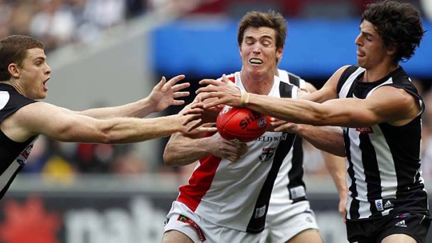 Lenny Hayes fends off a tackle by Heath Shaw (left) and Scott Pendlebury.