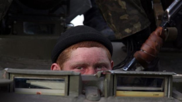 A soldier peeks out from behind a column of vehicles.