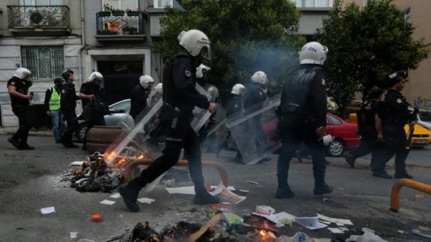 Protest: Police walk past burning debris in the Cihangir district of Istanbul.