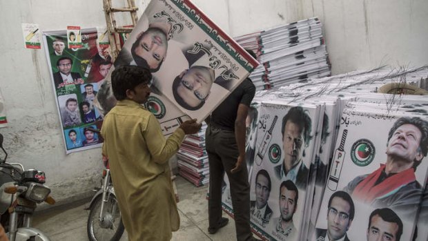 Party volunteers prepare  campaign posters of Imran Khan in Lahore ahead of Saturday's election.
