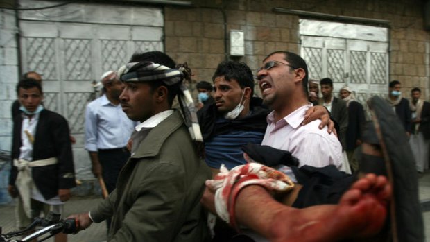 A Yemeni protester is carried on a motorcycle to hospital after deadly clashes between protesters and government troops.