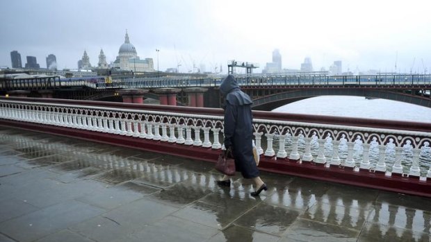 A pedestrian walks across a wet Blackfriars Bridge,  London.