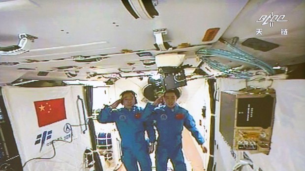 Two Chinese astronauts Jing Haipeng, left and Chen Dong salute in the space lab Tiangong 2.
