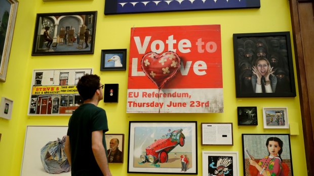 A man poses in front of British artist Banksy's "Vote to Love", spray paint on a UK Independence Party (UKIP) placard, and other works in the Royal Academy's annual exhibition in London.