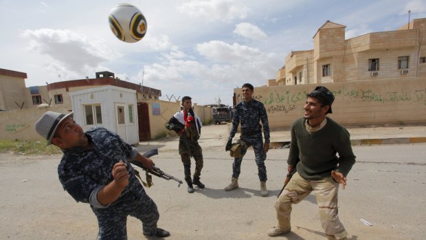 Members of the Iraqi security forces play football in Tikrit after taking it from Islamic State.