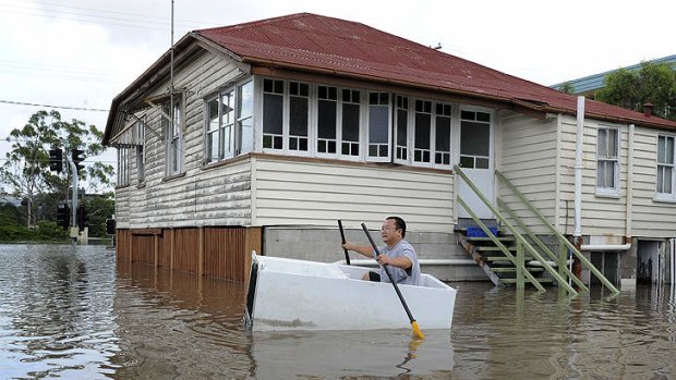 A man paddles in flood waters near his Brisbane home, in 2011.
