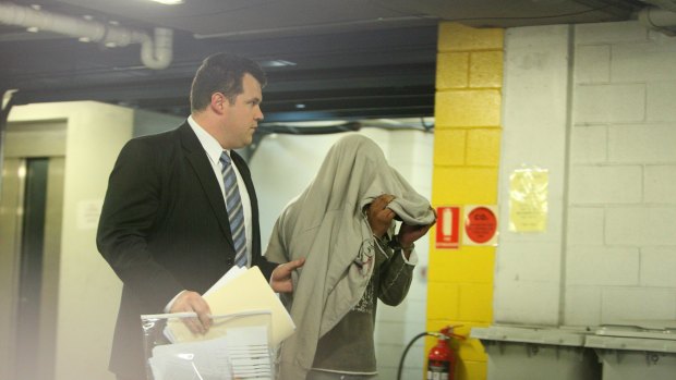 The man charged with attempted  murder  is led away at Merrylands police  station today.