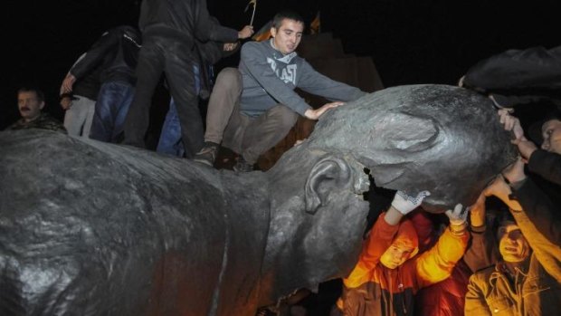 People react after a statue of Soviet state founder Vladimir Lenin was toppled by protesters during a rally organised by pro-Ukraine supporters in the centre of the eastern Ukrainian town of Kharkiv.