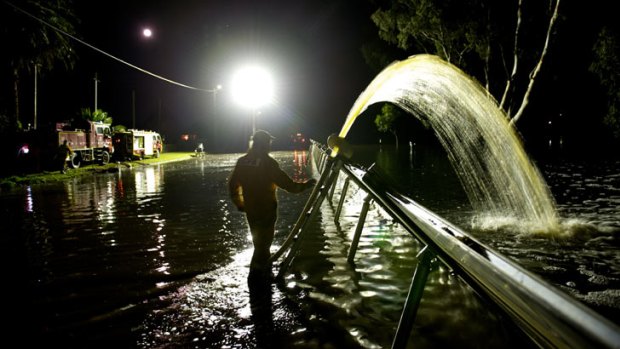 Firefighters try to pump water back over the levee after it was breached in Weir Street, Nathalia.