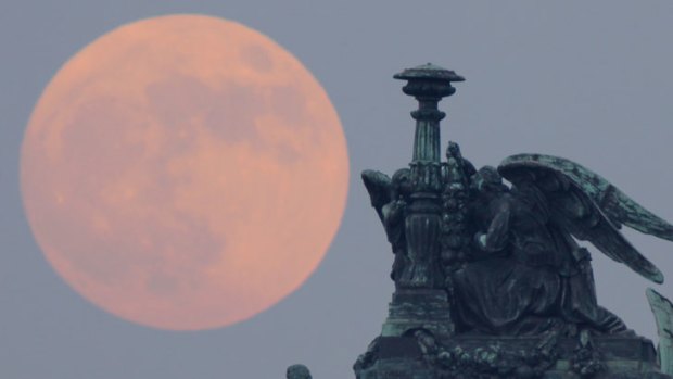 Super-sized: The full moon rises behind statues of angels fixed at the St Isaak's Cathedral in St Petersburg, Russia last night.