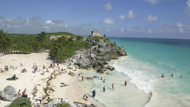 Tourists enjoy the beach near the Mayan ruins of El Castillo in Mexico.

