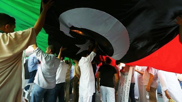 Libyans deploy a giant national flag during a rally in support of "Fajr Libya" (Libya Dawn).