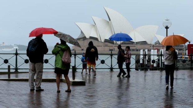 Take shelter: Tourists battle the rain at The Rocks.