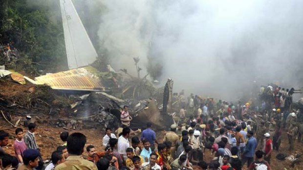 Firefighters rescue injured passengers as people crowd around the wreckage of the Air India plane in Mangalore.
