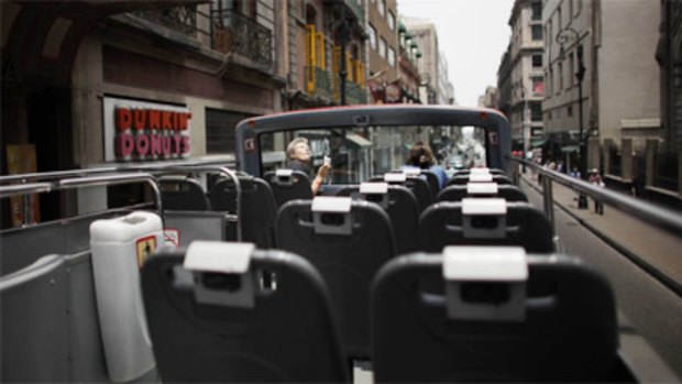 A tourist  takes pictures from an empty double decker tour bus as he rides through downtown Mexico City this week.