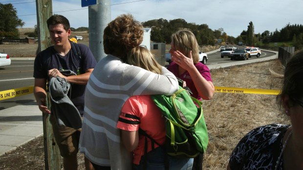 Grim toll: People console each other on a road leading to the Umpqua Community College campus in Roseburg on Thursday.