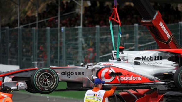 A crane lifts the car of McLaren Mercedes' driver Jenson Button after he crashed at the Spa-Francorchamps circuit.