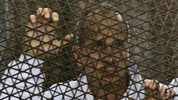 Al-Jazeera journalist and Australian citizen Peter Greste stands inside the defendants' cage in a courtroom during the trial.