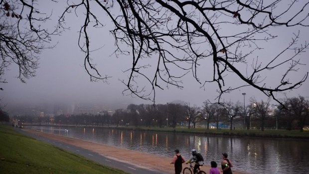 Joggers hit the road on a chilly and foggy Melbourne morning. 
