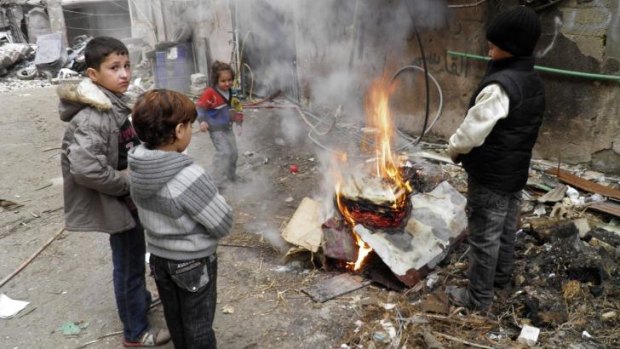 Children warm themselves around a fire in the besieged area of Homs.