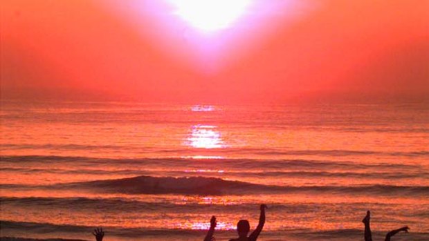 Fresh ... beachgoers dance as the sun rises over Hainan Island.