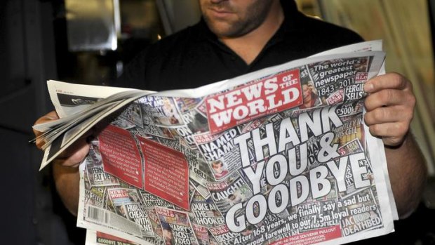 An employee looks at a copy of the final edition of British tabloid the News of the World.