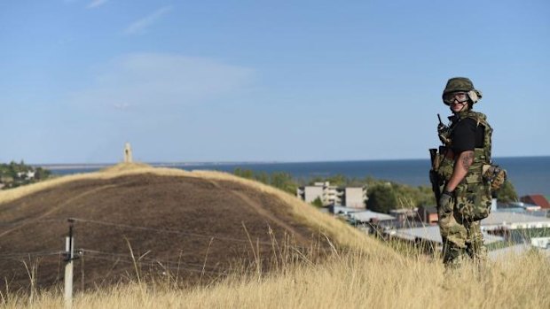 A Ukrainian fighter stands guard on a hill on the outskirts of Mariupol.