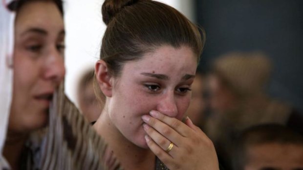 An Iraqi Yazidi woman who fled Sinjar, cries as she stands among others at a school where they are taking shelter.