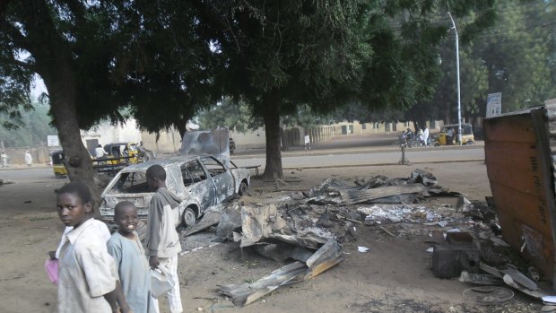 Children stand near the scene of an explosion in a mobile phone market in Potiskum, Nigeria ... two females were used as human bombs to target a busy marketplace, killing four people.