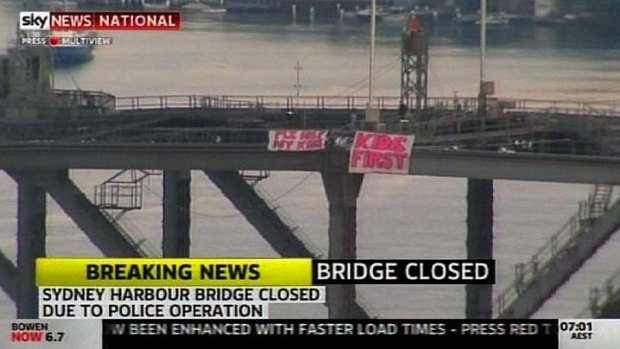Major delays ... a man has been arrested after unfurling these two banners on the Harbour Bridge.