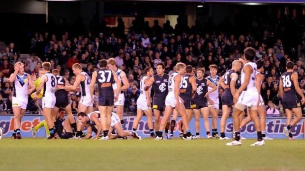 Carlton and Port Adelaide players congregate around the ball during a game in season 2013.