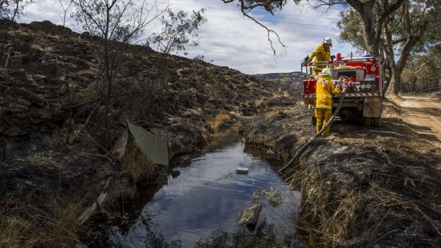 Firefighters near Yass fill up their truck from a creek.