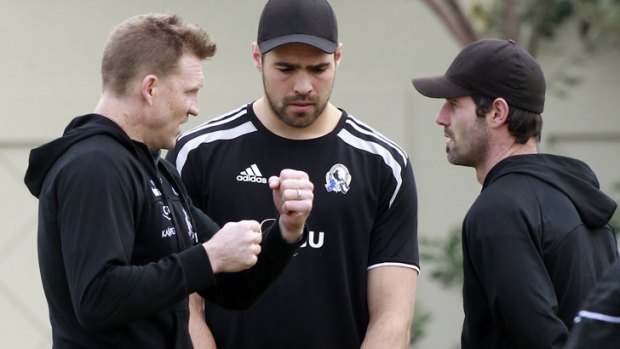 Collingwood coach Nathan Buckley, left, chats to injured forwards Chris Dawes, centre, and Alan Didak.