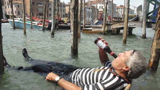 Drastic measures: A gondolier deals with a 32-degree day in Venice this week, drinking beer in a chair submerged in the Grand Canal.