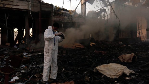 A man takes photos of the damage caused by the reception hall airstrike.