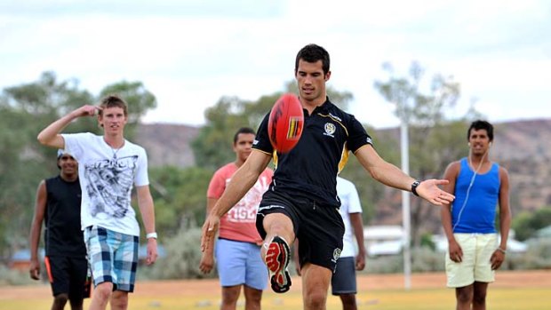 Alex Rance  has a kick with students of Centralian College in Alice Springs.