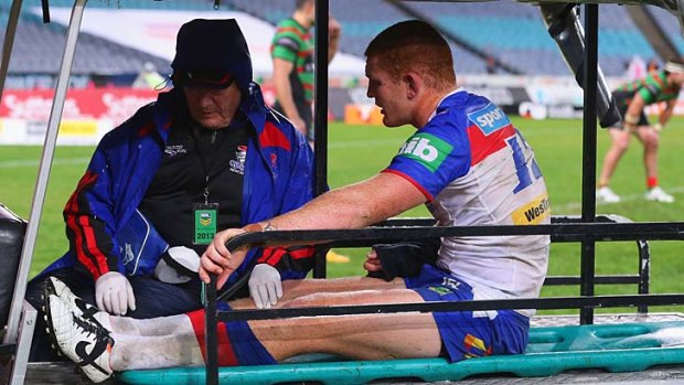Alex McKinnon of the Knights is taken from the field on a medicab after injuring his leg in a tackle.