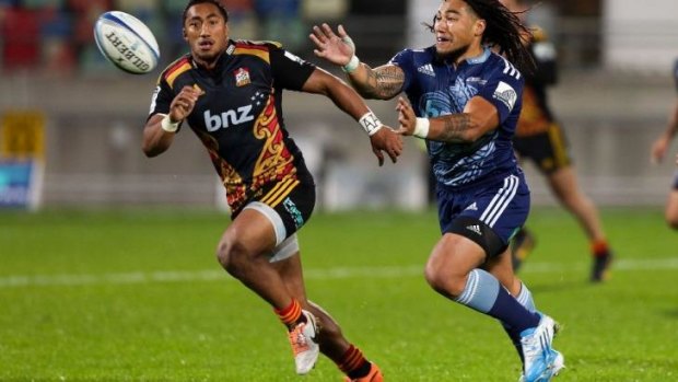 Ma'a Nonu of the Blues passes as Bundee Aki of the Chiefs looks on.