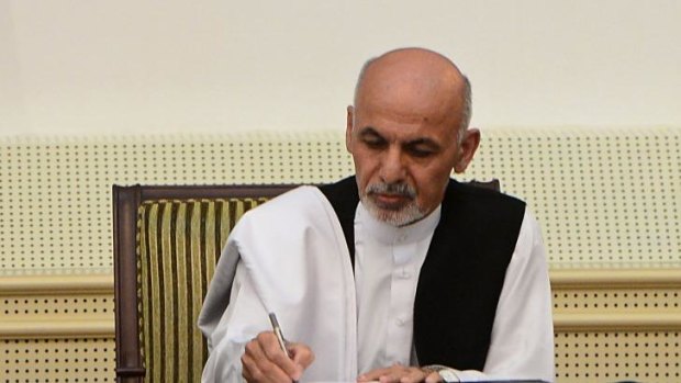 Afghan president Ashraf Ghani Ahmadzai signs a power-sharing agreement with unseen rival Abdullah Abdullah at the Presidential Palace in Kabul on September 21, 2014. 