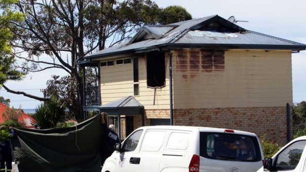 Grim task ... police inspect the burnt house yesterday.