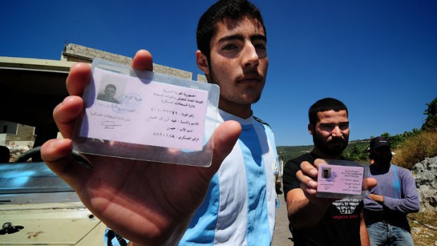 Newly defected soldiers from the Syrian Army show their military identifcation cards in Jabal Akrad.