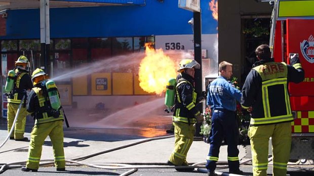 Flames shoot from gas bottles in a service station in King Street, Newtown, near the corner of Alice Street.