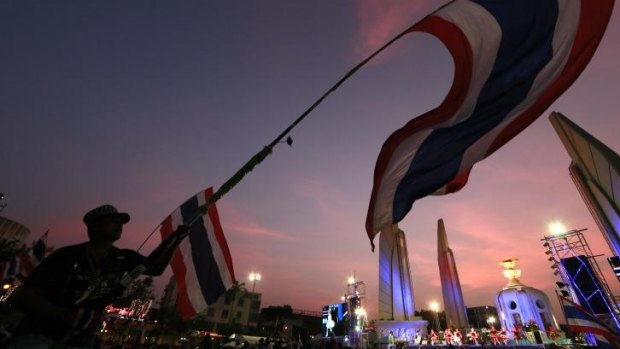 A Thai anti-government demonstrator waves the national flag during a New Year's Eve protest. 