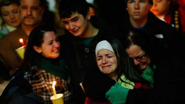 Donna Soto (right), mother of Victoria Soto, the first-grade teacher at Sandy Hook Elementary School who was shot and killed while protecting her students, hugs her daughter Karly (second from right) while mourning their loss with Victoria's other two siblings, Jillian (far left) and Matthew Soto (second from left), at a candlelight vigil at Stratford High School.