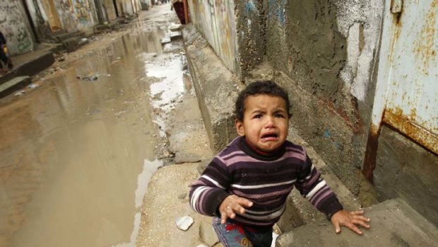 Vulnerable ... a Palestinian boy cries as he arrives at his home after walking through puddles in Shati refugee camp in Gaza City.