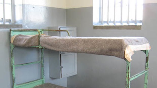 Simple beds with thin blankets at Robben Island prison.